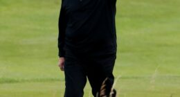 Donald Trump waving on a golf course.