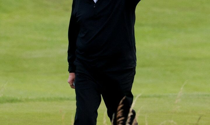 Donald Trump waving on a golf course.