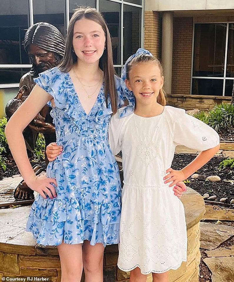 Two girls in dresses stand together near a statue.