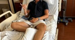 Teenager in hospital bed with bandaged foot, giving shaka sign.