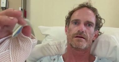 Man in hospital bed with bandaged hand.
