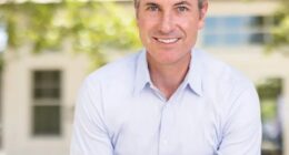 Portrait of a smiling man in a light blue shirt.