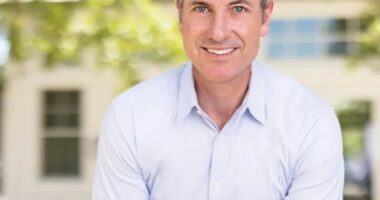 Portrait of a smiling man in a light blue shirt.