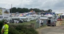 Screenshot of a large outdoor event with numerous RVs and tents.