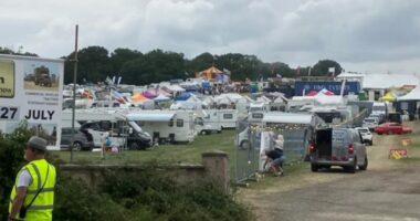 Screenshot of a large outdoor event with numerous RVs and tents.