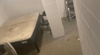 Basement room with mattress, fan, and chairs.