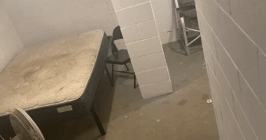 Basement room with mattress, fan, and chairs.