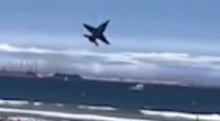 Jet plane flying low over a crowded beach.