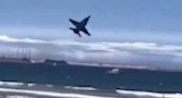 Jet plane flying low over a crowded beach.
