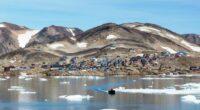 Kap Hope, Ittoqqortoormiit, Greenland, with colorful houses and ice floes in the water.