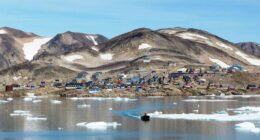 Kap Hope, Ittoqqortoormiit, Greenland, with colorful houses and ice floes in the water.