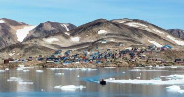 Kap Hope, Ittoqqortoormiit, Greenland, with colorful houses and ice floes in the water.
