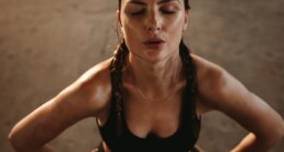 Fit woman with her hands on her hips taking deep breathe. Female athlete taking break after intense workout.