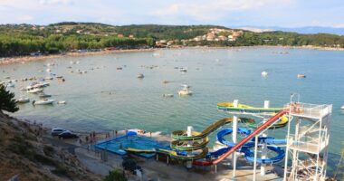 Aerial view of a beach with water slides and many boats.