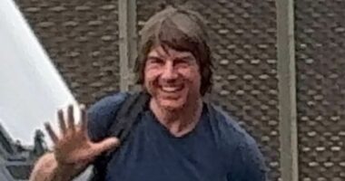 Tom Cruise grins and waves as he lands in London with Ana de Armas
