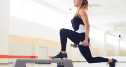 Young woman holding dumbbells while being in squat position in a health club. Fitness, sport, training, gym and lifestyle concept