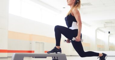 Young woman holding dumbbells while being in squat position in a health club. Fitness, sport, training, gym and lifestyle concept