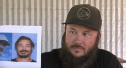 Man holding photos of murder suspect, mistakenly identified as suspect.