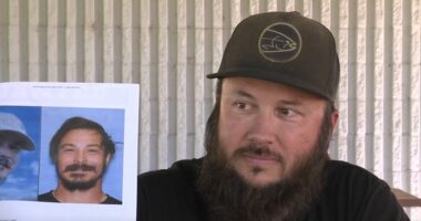 Man holding photos of murder suspect, mistakenly identified as suspect.