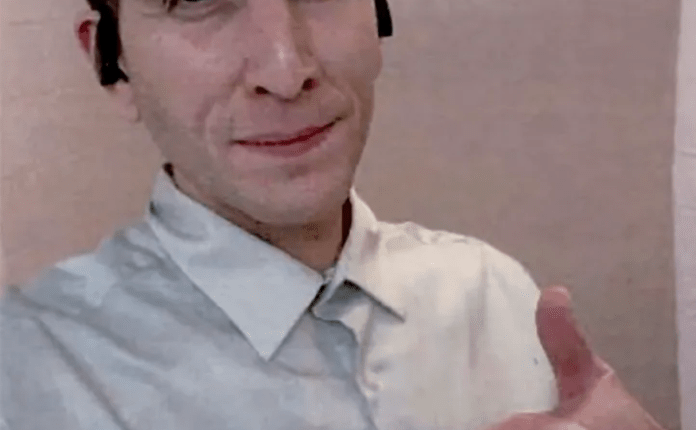 Man in a light gray shirt giving a thumbs up.