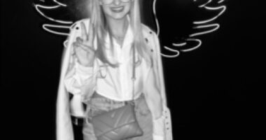 Black and white photo of Georgia Harry posing in front of a neon wing backdrop.
