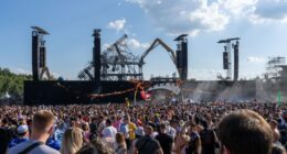 Crowd at Tomorrowland electronic music festival with damaged main stage being dismantled.