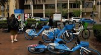 Pedestrians walk past e-bikes near the NSW State Library in Sydney.