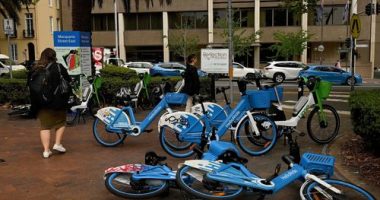 Pedestrians walk past e-bikes near the NSW State Library in Sydney.