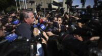 Brazil's former President Jair Bolsonaro is surrounded by the press as he leaves the Secretariat of Penitentiary Administration where he arrived after the Supreme Court ordered him to be fitted with an electronic ankle monitor in Brazil.