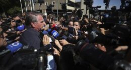 Brazil's former President Jair Bolsonaro is surrounded by the press as he leaves the Secretariat of Penitentiary Administration where he arrived after the Supreme Court ordered him to be fitted with an electronic ankle monitor in Brazil.
