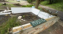 A Camp Mystic sign is seen near the entrance to the establishment along the banks of the Guadalupe River after a flash flood swept through the area in Hunt, Texas, Saturday, July 5, 2025. (AP Photo/Julio Cortez)