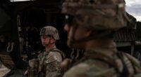 A man is halted climbing the US-Mexico border wall. Under new Trump rules, US troops sound the alarm