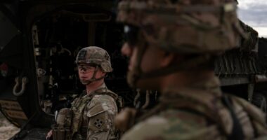 A man is halted climbing the US-Mexico border wall. Under new Trump rules, US troops sound the alarm