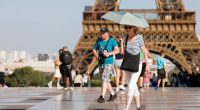 A tourist holds an umbrella as protection from the sun during a heatwave near the Eiffel Tower, in Paris, on June 30, 2025. French authorities put Paris on red alert for extreme heat.