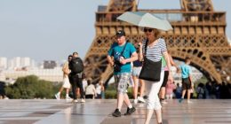 A tourist holds an umbrella as protection from the sun during a heatwave near the Eiffel Tower, in Paris, on June 30, 2025. French authorities put Paris on red alert for extreme heat.