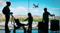 mother with kids and luggage looking at planes in airport, family travel