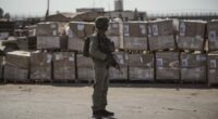 FILE - An Israeli soldier stands beside humanitarian aid packages awaiting pickup on the Palestinian side of the Kerem Shalom crossing in the Gaza Strip, Thursday, July 24, 2025, during a media tour organized by the Israeli army. (AP Photo/Ohad Zwigenberg, file)