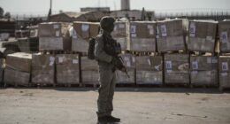 FILE - An Israeli soldier stands beside humanitarian aid packages awaiting pickup on the Palestinian side of the Kerem Shalom crossing in the Gaza Strip, Thursday, July 24, 2025, during a media tour organized by the Israeli army. (AP Photo/Ohad Zwigenberg, file)