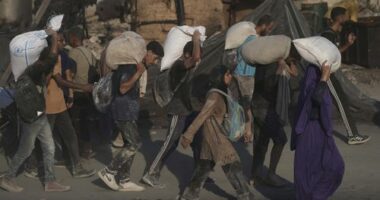Palestinians carry sacks of flour unloaded from a humanitarian aid convoy that reached Gaza City from the northern Gaza Strip.