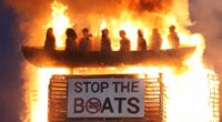 Police launch hate crime investigation as 'vile and racist' effigy of small boat migrants is burned on top of Northern Ireland bonfire