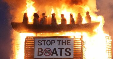 Police launch hate crime investigation as 'vile and racist' effigy of small boat migrants is burned on top of Northern Ireland bonfire