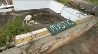 A Camp Mystic sign is seen near the entrance to the establishment along the banks of the Guadalupe River after a flash flood swept through the area in Hunt, Texas, Saturday, July 5, 2025. (AP Photo/Julio Cortez)