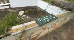 A Camp Mystic sign is seen near the entrance to the establishment along the banks of the Guadalupe River after a flash flood swept through the area in Hunt, Texas, Saturday, July 5, 2025. (AP Photo/Julio Cortez)