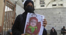Esraa Abu Halib shows to journalists a photo of her 5-month-old baby, Zainab, who died from malnutrition-related causes, according to the family and the hospital, as she stands outside the Nasser Hospital, in Khan Younis, Gaza Strip, Saturday, July 26, 2025. (AP Photo/Mariam Dagga)