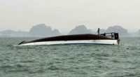 People stand on a tourist boat that capsized in Halong Bay on Saturday.