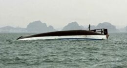People stand on a tourist boat that capsized in Halong Bay on Saturday.