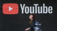 A young woman wearing headphones walks past a billboard advertisement for YouTube on September 27, 2019 in Berlin, Germany. YouTube has evolved as the world's largest platform for sharing video clips. (Photo by Sean Gallup/Getty Images)