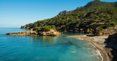 Secluded cove with clear turquoise water and a small beach.