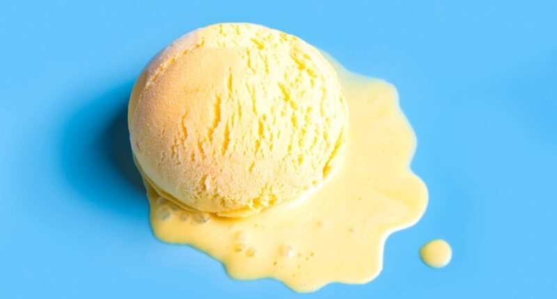 Summer creative concept with melting yellow ice cream scoop on blue background, copy space. Trendy beach relax and summer vacation theme.