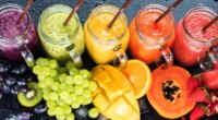 Fresh Color Juices Smoothie Violet Green Yellow Orange Red from Tropical Fruits Kiwi Water Melon Strawberry Apple Orange Banana Pine Apple Mango Pomegranate Grape Bottles Rainbow Dark Background